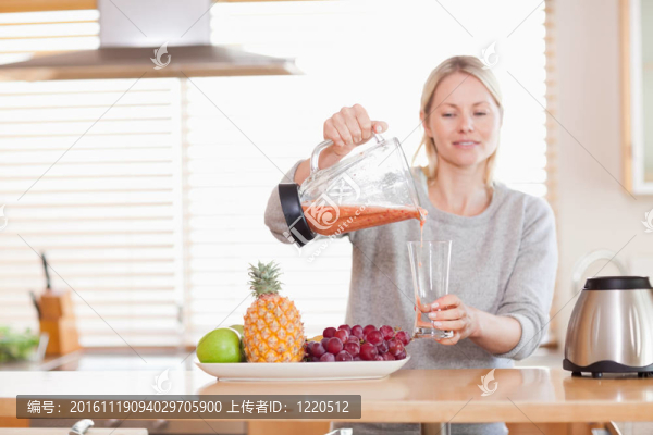 女人把自制的果汁倒入玻璃杯