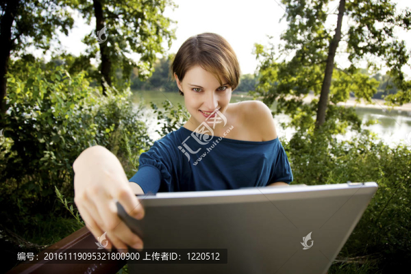 在公園里帶著筆記本電腦的年輕女子