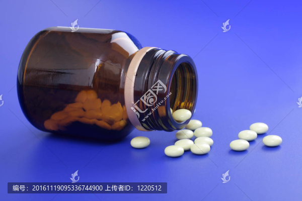 溢出的藥片和藥瓶。藍色背景片