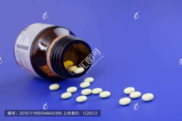 溢出的藥片和藥瓶。藍(lán)色背景片