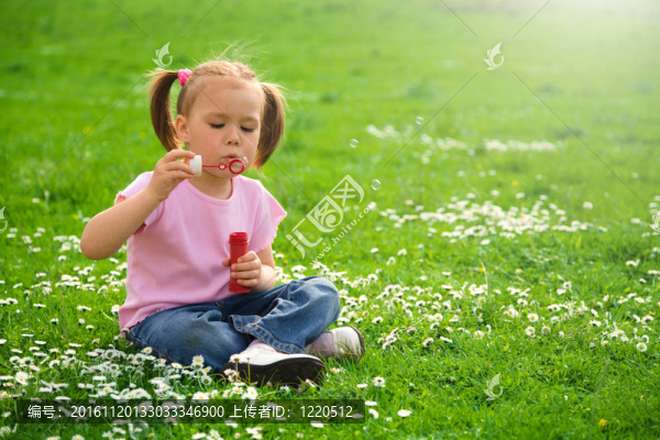 小女孩坐在綠色的草地上