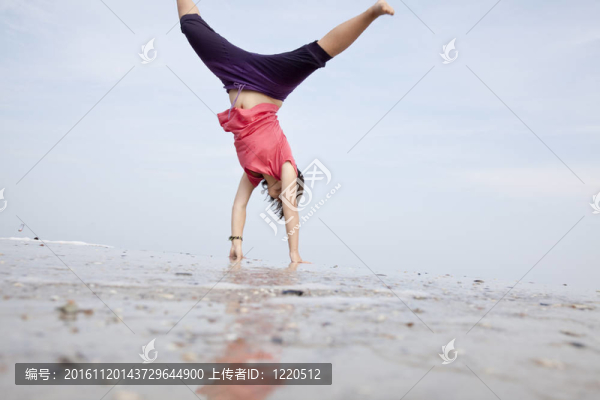 年輕的女孩表演雜技的海灘上。