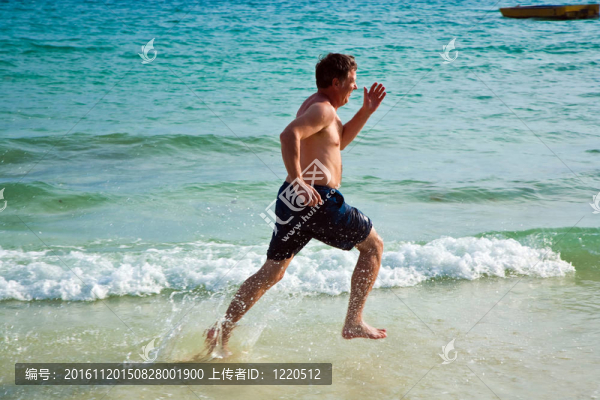 男人在美麗的海灘上奔跑，享受著水