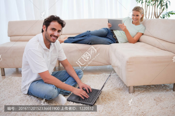當她的男朋友在起居室里使用筆記本時，女人正在使用平板電腦.