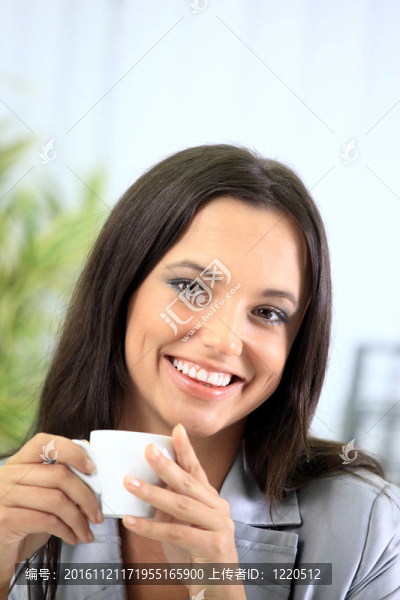 在辦公室的一個聰明的年輕女商人看報紙喝咖啡的肖像