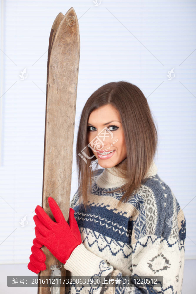 年輕的女子在冬季毛衣持有舊木滑雪肖像