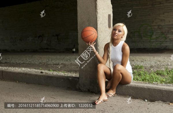 漂亮的金發(fā)女孩坐在街上打籃球