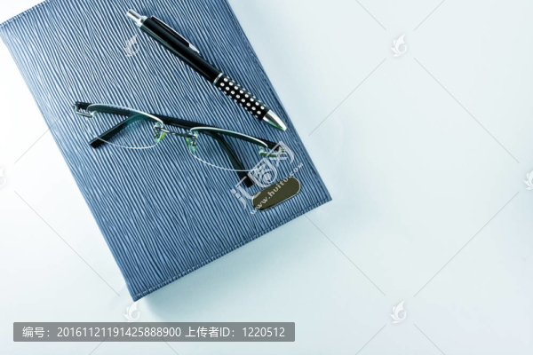 藍色筆記本上的眼鏡與黑色筆隔離