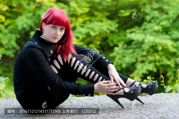 性感的年輕女孩與紅色的頭發(fā)在黑色的衣服在公園休息