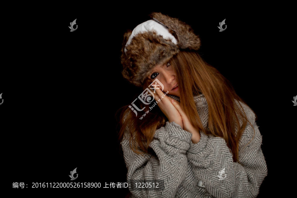 年輕漂亮的金發(fā)女人，戴著溫暖的冬帽和灰色外套；黑色背景