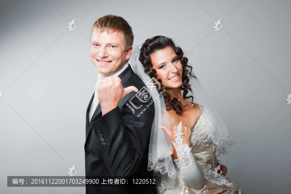 年輕美麗幸福的新婚新娘和新郎的手勢在灰色背景的工作室肖像
