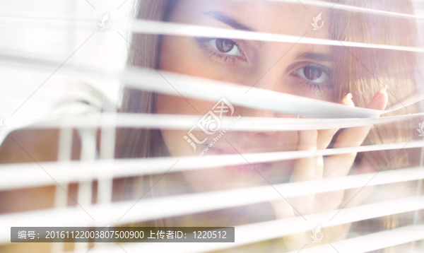 漂亮的女孩看了看百葉窗