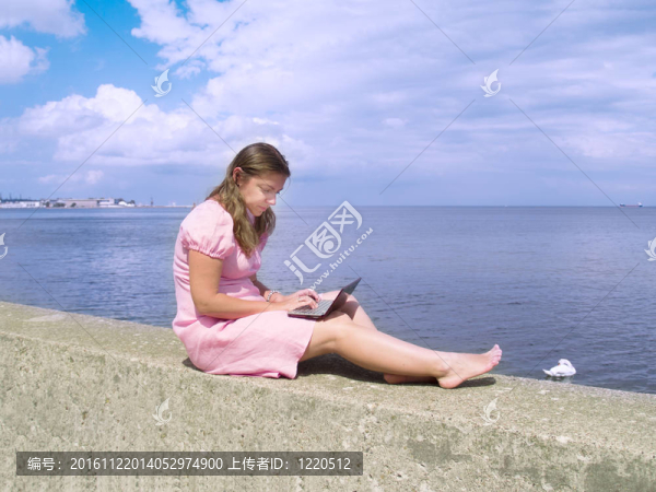 女人用筆記本電腦旁邊的海邊