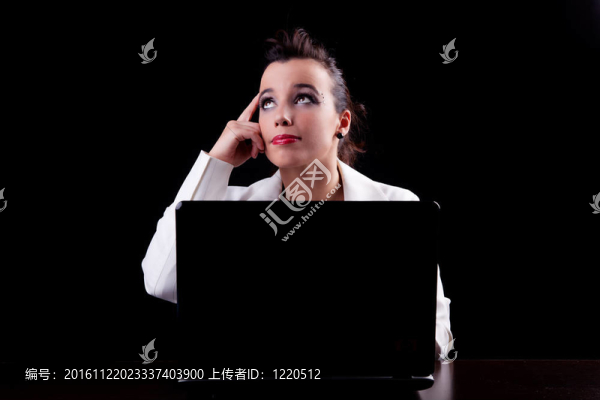 電腦上的漂亮女人；思考向上看；在黑色背景下孤立。工作室拍攝。