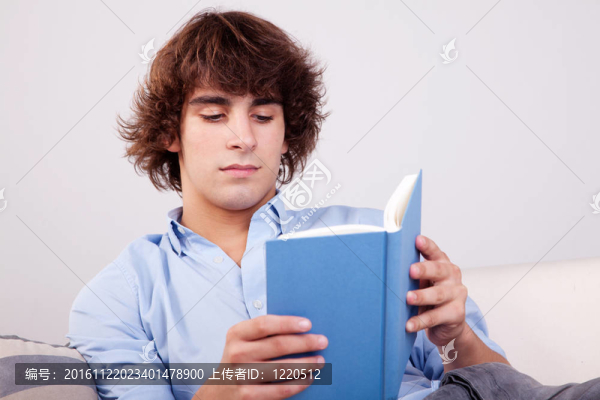 坐在沙發(fā)上看一本書的人