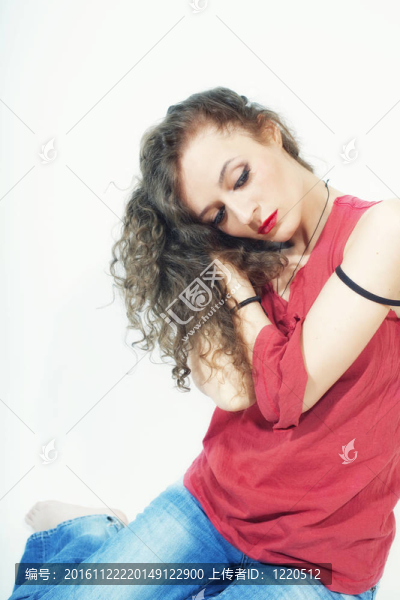 美麗的卷曲的黑發(fā)女人在紅色的T恤和藍(lán)色牛仔褲
