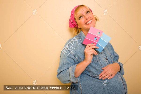 憂郁的孕婦持粉紅色和藍色油漆色板