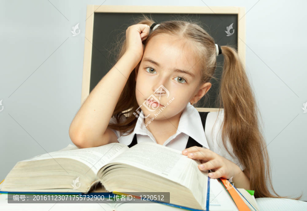 學(xué)校女孩在書堆后面做作業(yè)。