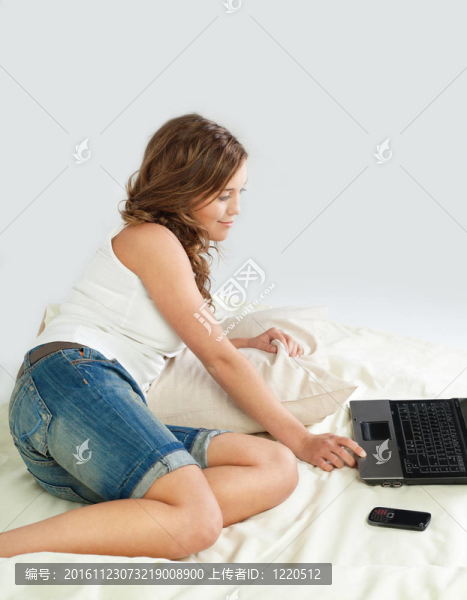 輕松的年輕女子在床上與筆記本電腦