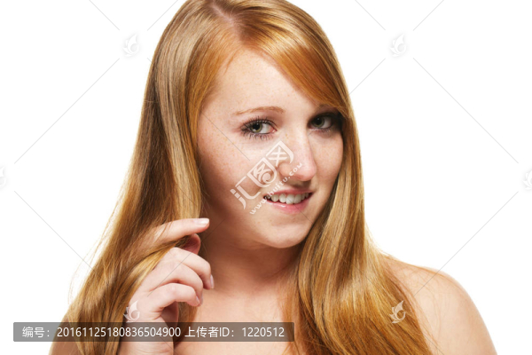 年輕的紅發(fā)女人玩弄她的頭發(fā)在白色背景