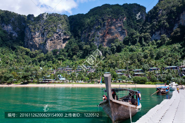 長(zhǎng)尾船停泊在浮橋與海灘和雨林的背景