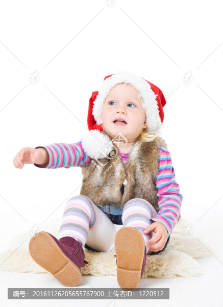 一個(gè)穿著毛皮夾克和紅Santa帽子的金發(fā)女孩坐在地板上