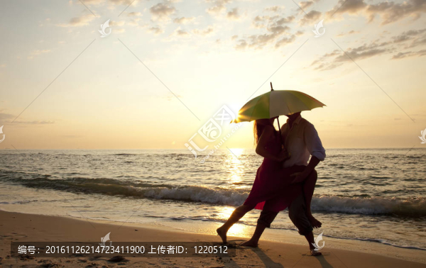 在日落時(shí)在沙灘上接吻的情侶。