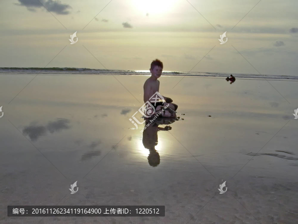 落日和倒影在海灘上的男孩