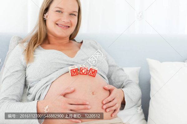 金發(fā)孕婦懷著媽媽的信躺在肚子上躺在家里的床上