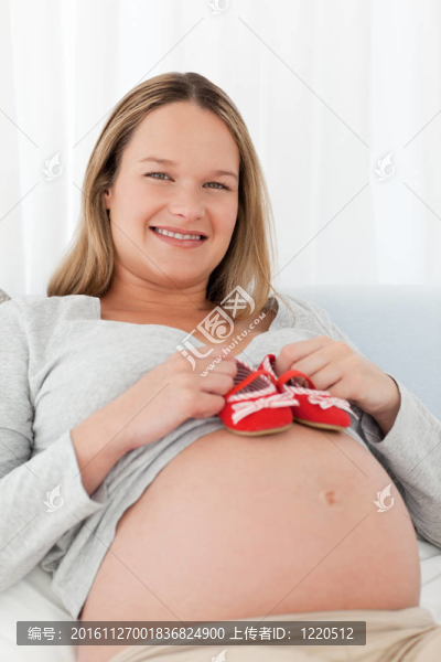 孕婦把嬰兒鞋放在肚子上