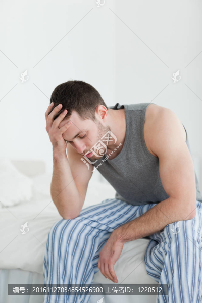 一個精疲力竭的男人坐在床上的畫像