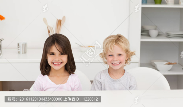 可愛的兄妹坐在廚房的一張桌子旁