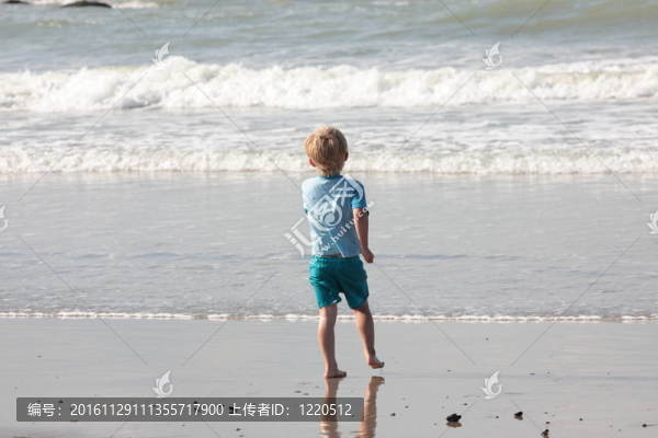 年幼的孩子走在沙灘上的波浪