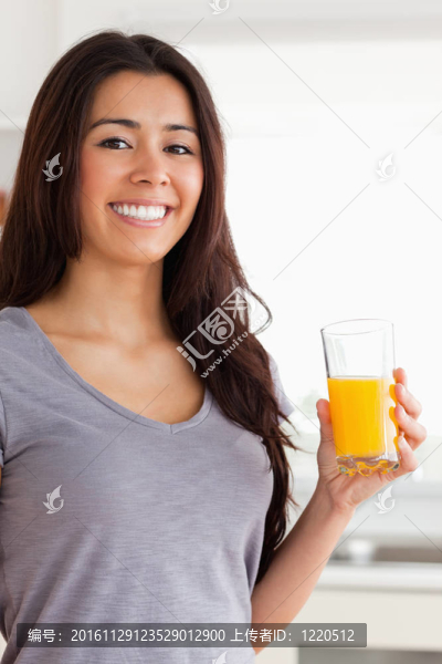 美女站著拿著一杯橙汁