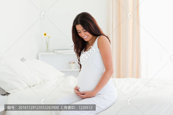 孕婦坐在床上摸肚子