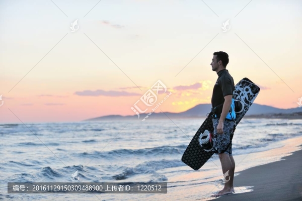 一個年輕人在海灘上的日落kitsurf肖像