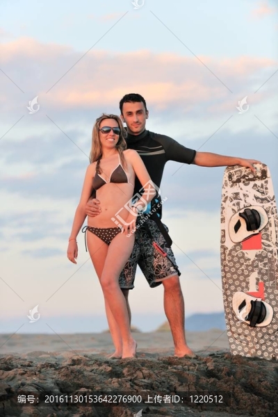 在日落時(shí)在海灘上擺姿勢的沖浪夫婦