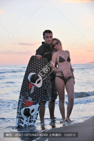 在日落時(shí)在海灘上擺姿勢的沖浪夫婦
