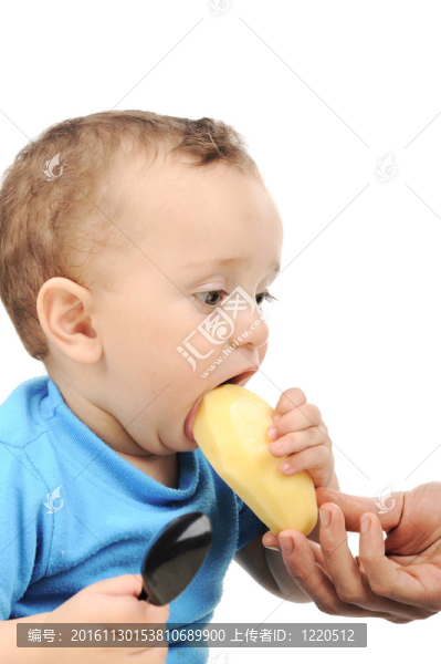 可愛的可愛的一歲的嬰兒在桌子上吃綠色的眼睛；勺子和盤子