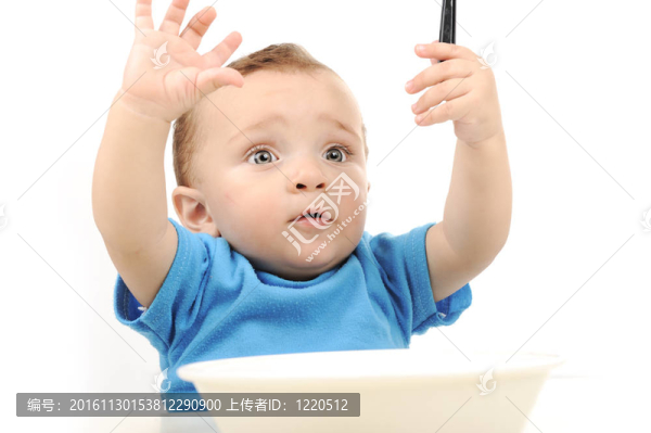 可愛的可愛的一歲的嬰兒在桌子上吃綠色的眼睛；勺子和盤子