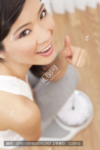 亞洲華人女子豎起大拇指衡量自己的尺度