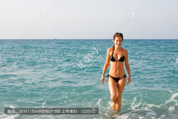 美麗的年輕女子在海灘上行走