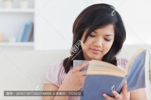 女人一邊捧著杯子一邊看書