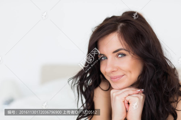 微笑的女人在她的白被子躺