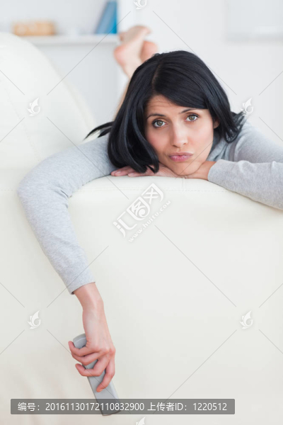 悲傷的女人在沙發(fā)上拿著電視遙控器