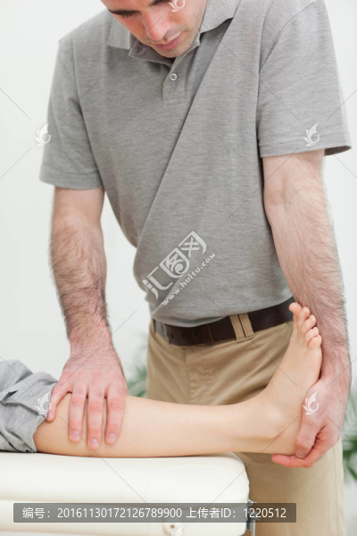嚴(yán)重的理療師拉伸一個病人的腿