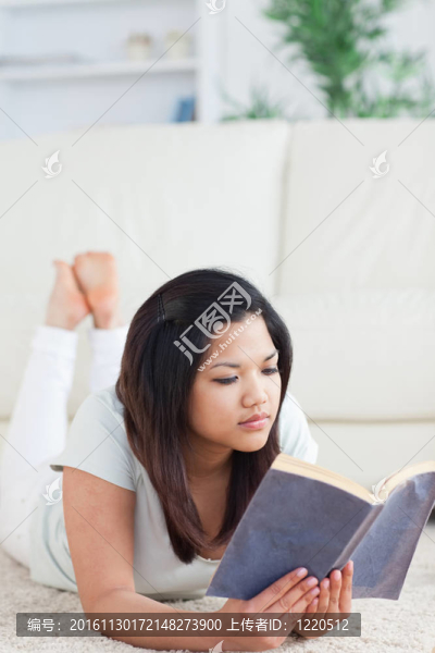 躺在地板上的女人讀一本書