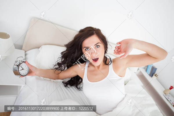 女人抱著鬧鐘打哈欠