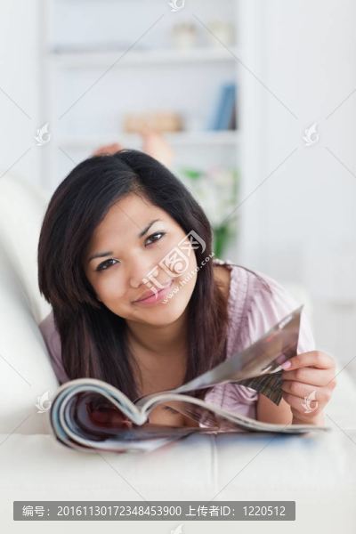女人在沙發(fā)上休息，手里拿著一本雜志