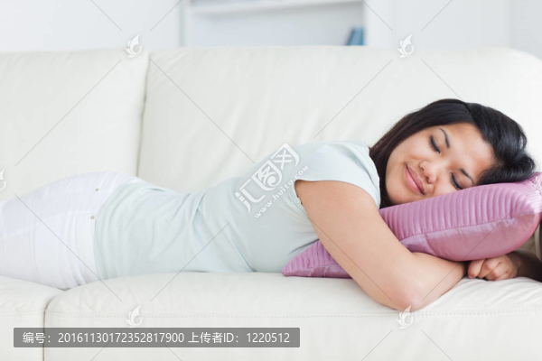 女人睡在白色沙發(fā)上，拿著枕頭